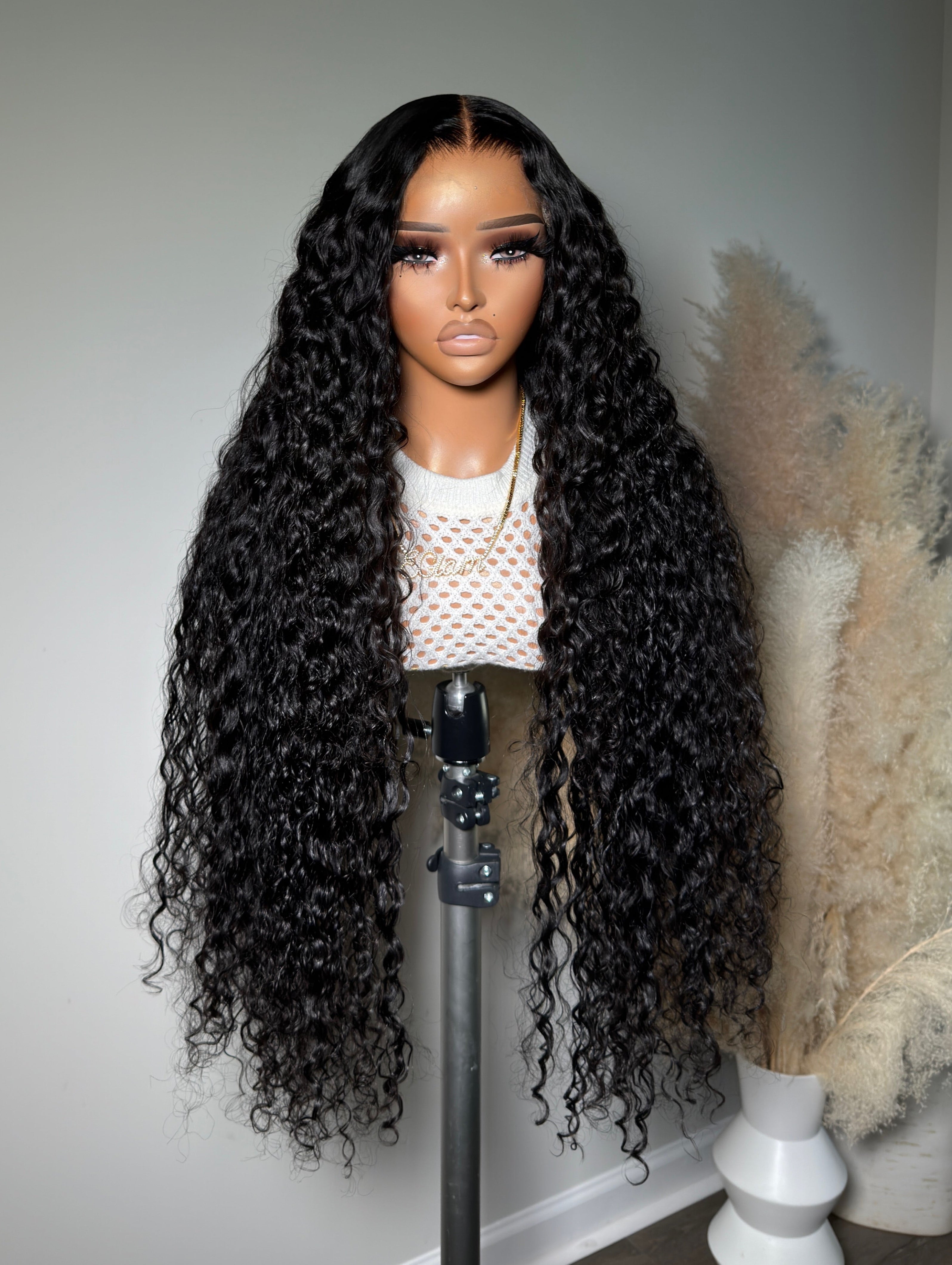 A mannequin head displaying a wig with curly hair, wearing a white top with a heart pattern.